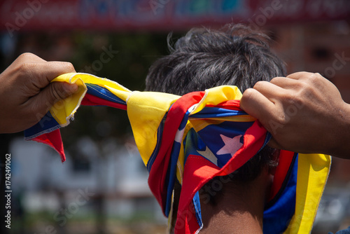 A protester adjusts a Venezuelan flag as a mask during a citizen protest.
