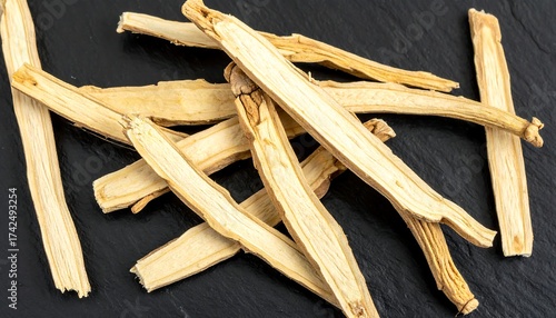 Dried, sliced medicinal root pieces on a dark surface