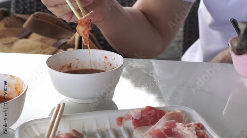 The final step: delicious Moo Krata pork, freshly cooked on the grill, is dipped into the essential spicy sauce before being enjoyed. Dynamic, appetizing, close-up footage.