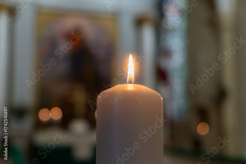 Single burning candle in church interior — symbol of prayer, faith and hope in sacred silence