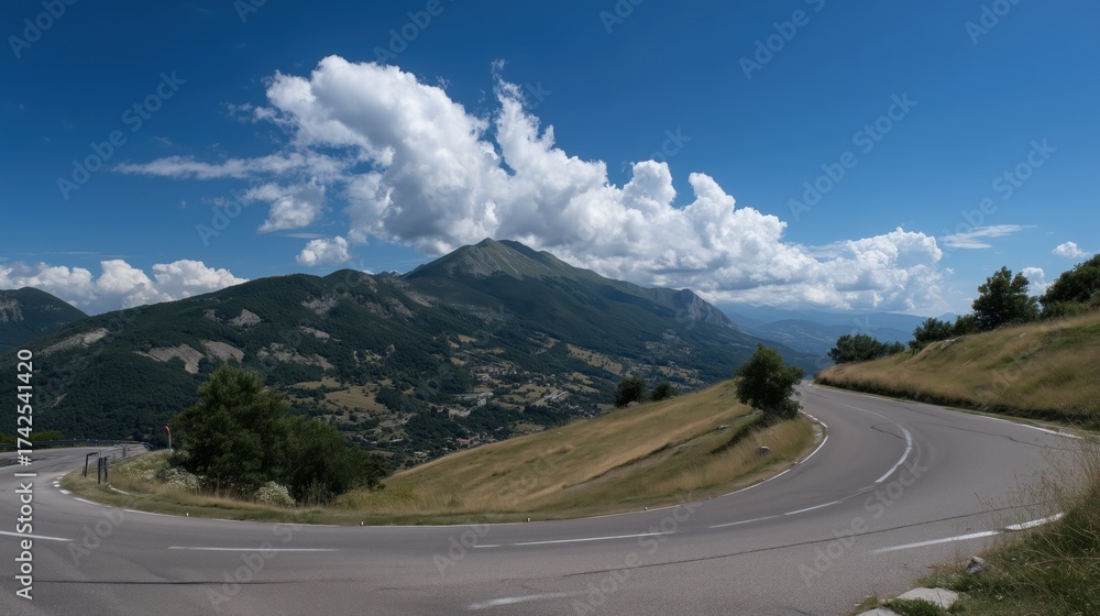 Fototapeta premium Mountainous Scenic Road with Curves and Lush Greenery under a Bright Blue Sky with Clouds