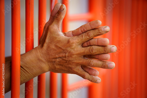 Hands Reaching Through Vertical Bars in an Orange Background