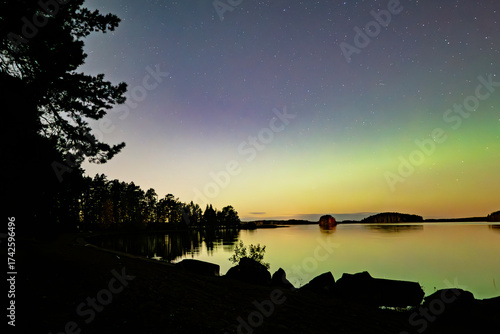 Amazing aurora borealis dancing over calm lake in >Farnebofjarden national park in  north of Sweden.