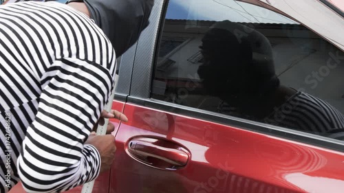 Masked thief breaking into car using metal tool, concept of crime, car theft, danger, and security risk. Symbol of illegal activity, vehicle protection awareness, and personal safety in urban areas