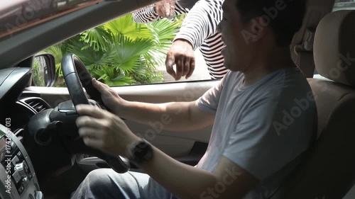 Masked thief threatening driver through car window during attempted robbery. Concept of car crime, carjacking, danger, security awareness, and personal safety in urban environments