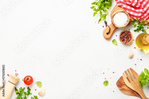 Spices, herbs and vegetables with olive oil on white kitchen table.