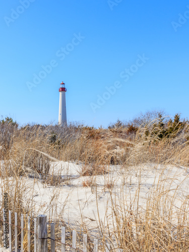 Lighthouse standing tall against blue sky and sandy dunes near a coastal area on a sunny day