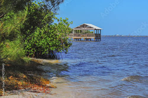 Front view, far distance of, a wood, observation platform, extended into the Indian river lagoon, under a tropical mid-afternoon blue sky