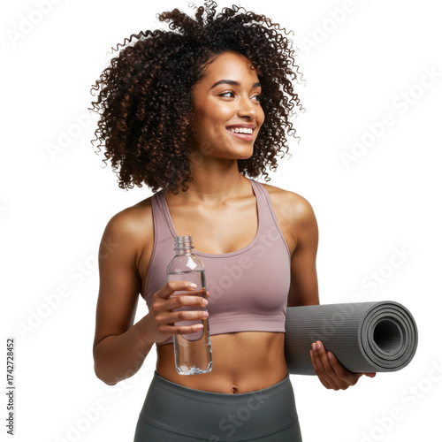 Smiling woman with curly hair holding water bottle and yoga mat.