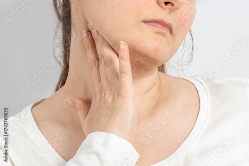 Woman over 35 holding her throat with her hand. Neck pain, lymph node