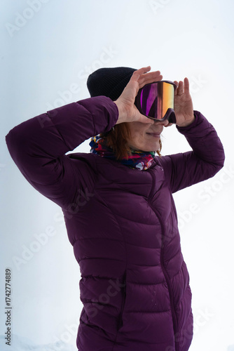 Woman in purple jacket looking through ski goggles on mountain slope