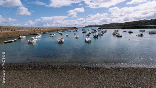 Schiffe in einem kleinen Hafen in der Bretagne in Frankreich mit einer Kaimauer als Begrenzung.