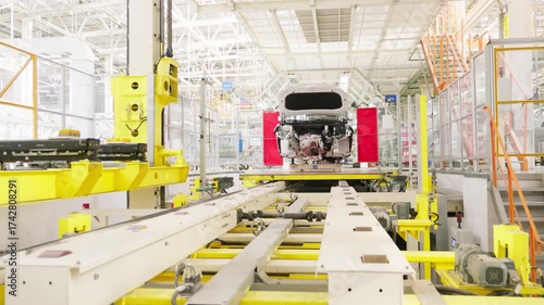 Moving conveyor nodes transporting car bodies through an automated assembly line at a modern automotive factory.