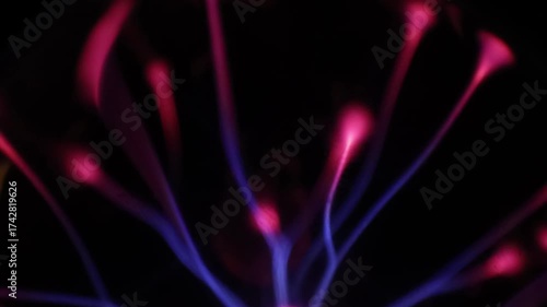 A stunning plasma globe radiates vibrant blue and pink electric arcs from its core, creating a mesmerizing and colorful display of static energy in the dark.