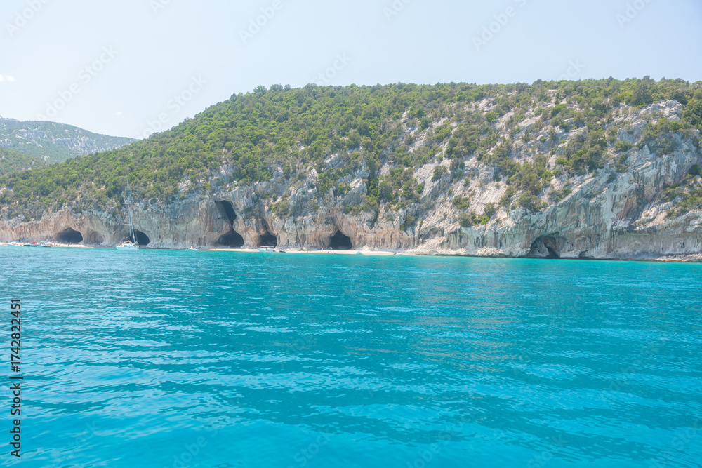 Fototapeta premium Mediterranean seascape with cliffs, clear turquoise water and green hills, Cala Luna, Sardinia, Italy