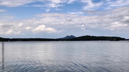Enjoy a serene lake view framed by majestic mountains and dramatic clouds in the sky