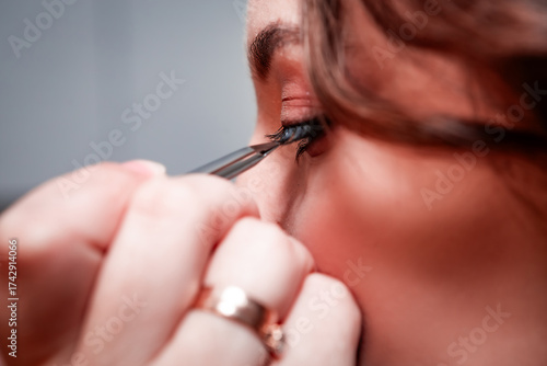 Makeup artist does eyelash extensions to a beautiful young pretty girl in a professional salon. Beauty, fashion and skin care industry. The work of a makeup artist. False eyelashes.	