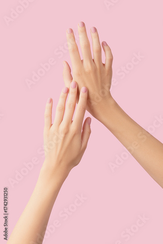 Beautiful groomed womans hands with pink matte nail design on a pink background. Manicure, pedicure beauty salon