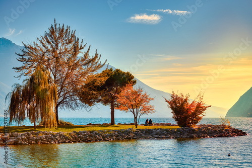 View of beautiful Lake Garda surrounded by mountains, Panoramic autumn view of sunset over Lake Garda in the evening with beautiful sunset colors, Italy