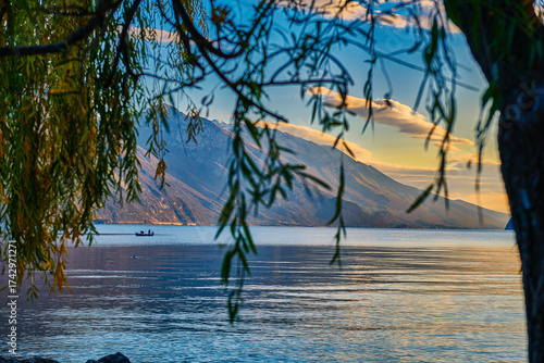 View of beautiful Lake Garda surrounded by mountains, Panoramic autumn view of sunset over Lake Garda in the evening with beautiful sunset colors, Italy