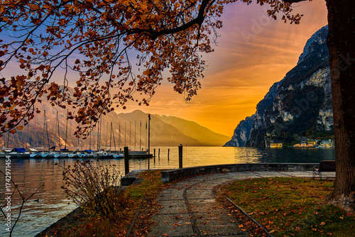 View of beautiful Lake Garda surrounded by mountains, Panoramic autumn view of sunset over Lake Garda in the evening with beautiful sunset colors, Italy