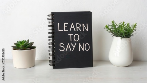 Black notebook with Learn to Say No text on white desk