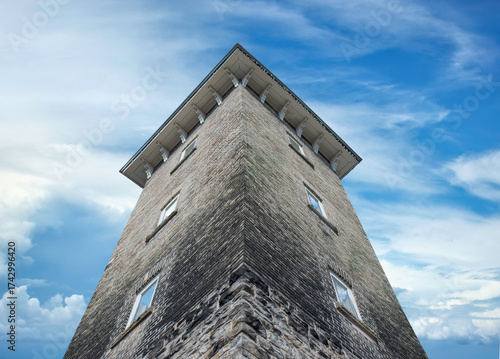 Dramatic view up of an old limestone tower and the sky above, reflections in windows, daytime, nobody
