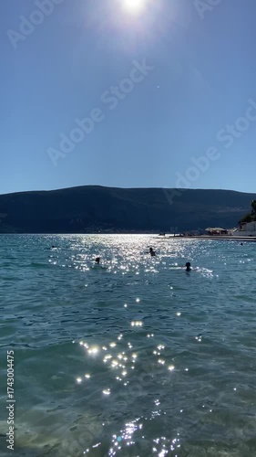 People swimming in the sea with sunlight reflections