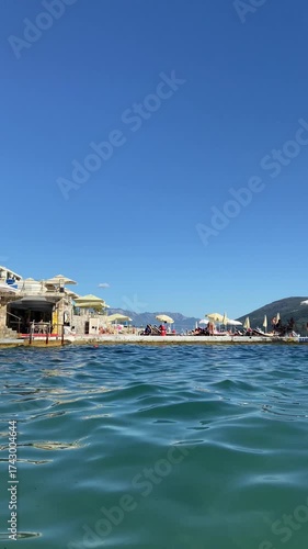View from the water of a beach with mountains and umbrellas