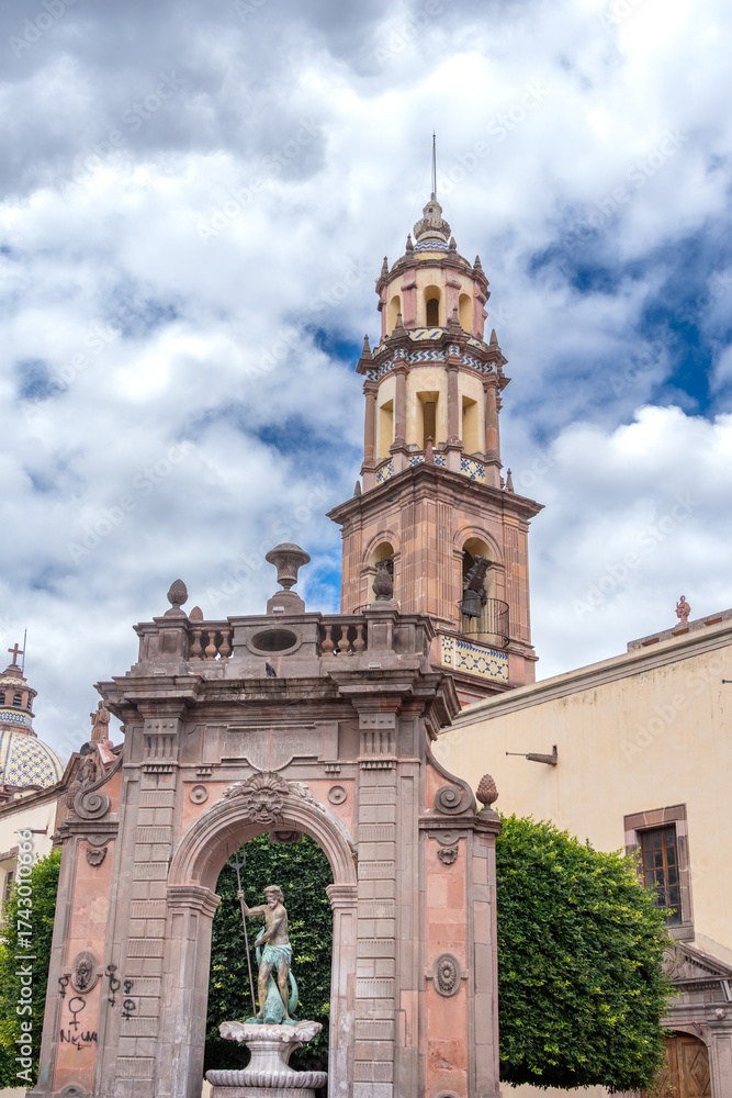 Obraz premium A beautiful building with a tall tower and a fountain in front of it. Historic center of Querétaro, colonial architecture, decorations for the celebration of Mexico's Independence Day.
