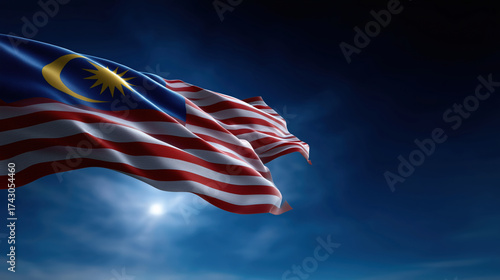 Waving Malaysian flag against a dramatic sky at night