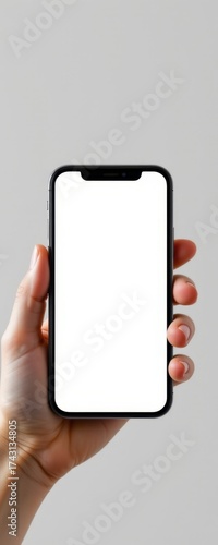 Close-up of a hand holding a modern smartphone with a blank white screen against a plain light gray background