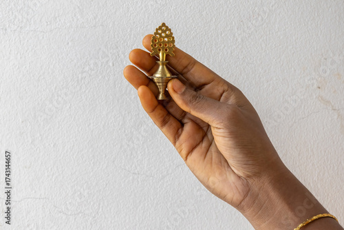 Close-up of a female hand holding an ornate Antique Brass Surmadani (Kohl or Kajal holder). Traditional cosmetic eyeliner container. Ethnic makeup and cultural beauty tool concept.
