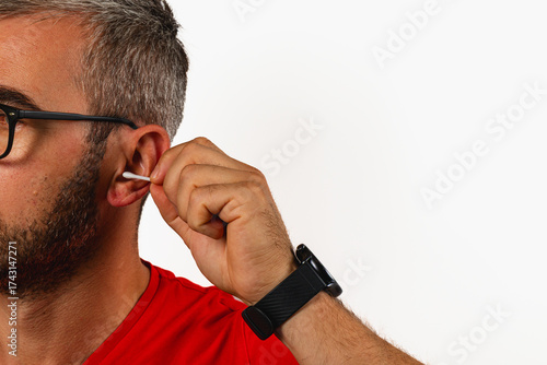 Man cleaning ear with cotton swab while wearing glasses and a red shirt