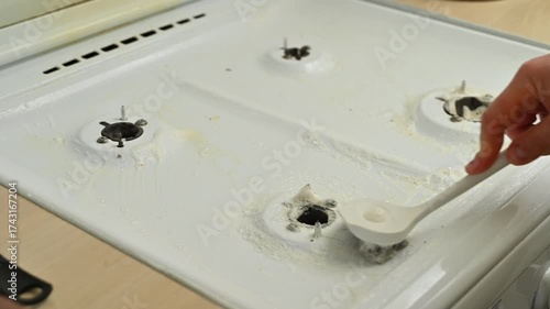 Person scrubbing white stove with brush
