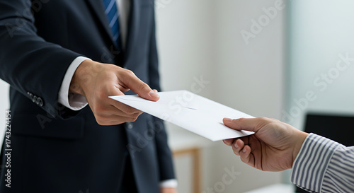 Photos Close-up image of hands passing a white business envelope, suggesting a contract