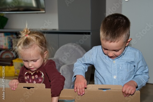 Little brother and sister opening present in cardboard box