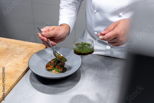 Fotografi Un chef cuisinant un plat raffiné en cuisine, illustrant un geste professionnel et une préparation gastronomique soignée avec des ingrédients de qualité