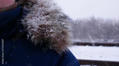 Wallpaper Mural Close-up of a teenager in a winter jacket with a fluffy collar, snowflakes falling and settling on the fur. A snowy park in the background, creating a serene winter scene. Perfect image for Torontodigital.ca