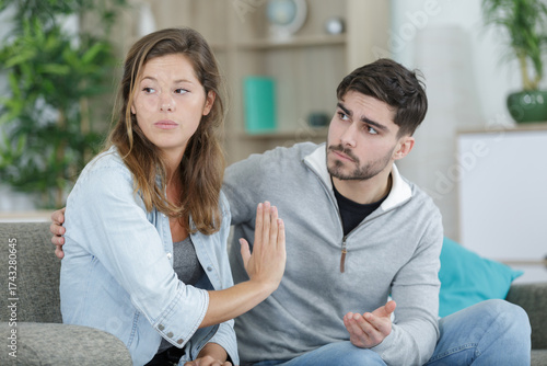 resentful girl sitting next to boyfriend on couch at home