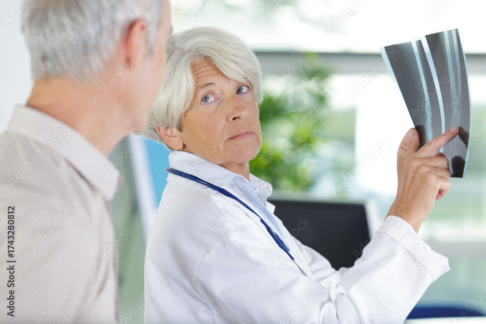 Fototapeta premium mature female doctor looking at an x-ray