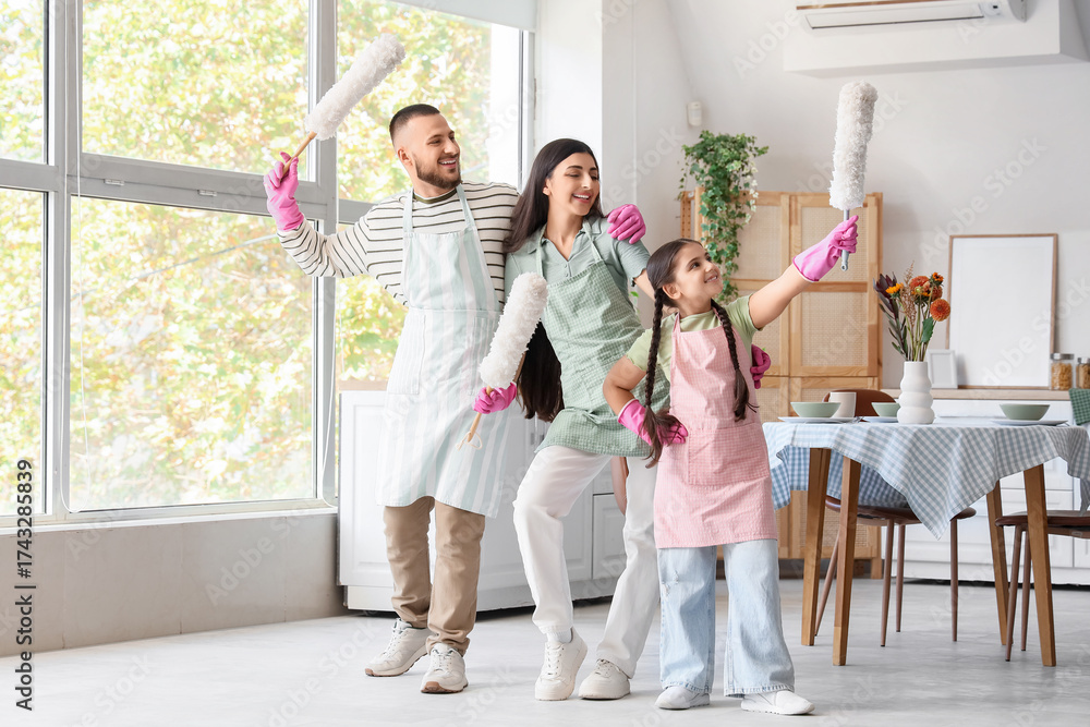 Naklejka premium Happy family with pp-dusters dancing while cleaning in kitchen