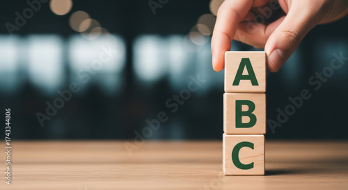 Hand stacking wooden blocks abc representing business basics learning and development