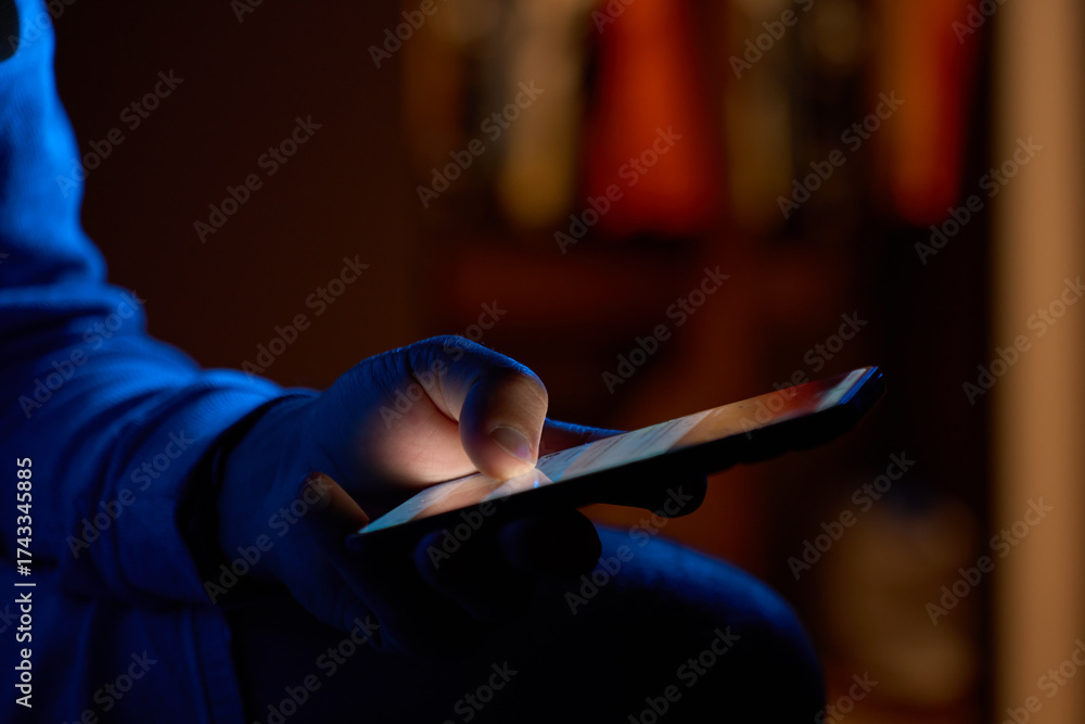 custom made wallpaper toronto digitalMan using smartphone at night. Close up of hand holding smartphone, swiping and scrolling social media feed on glowing screen in dark room