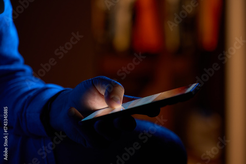 Wallpaper Mural Man using smartphone at night. Close up of hand holding smartphone, swiping and scrolling social media feed on glowing screen in dark room Torontodigital.ca
