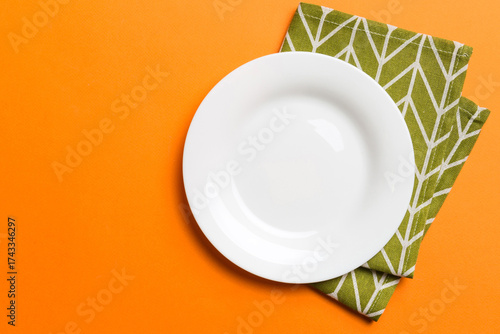 Top view on colored background empty round white plate on tablecloth for food. Empty dish on napkin with space for your design
