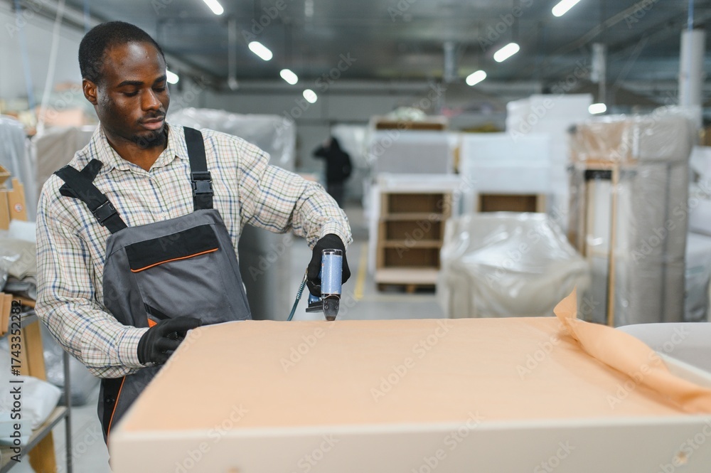 Fototapeta premium African american Furniture maker upholstering furniture in a warehouse