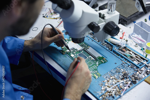 Electronics repair technician working under microscope