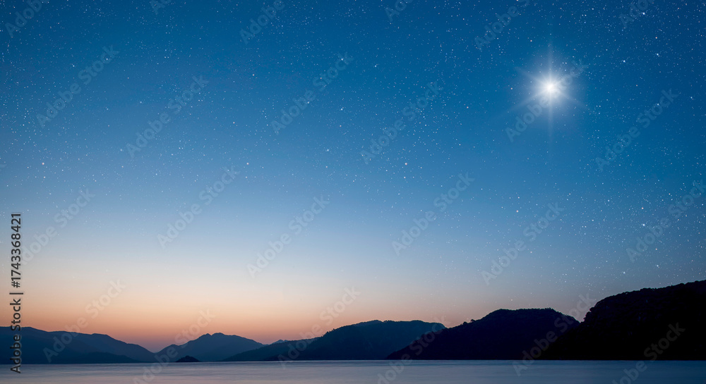 Fototapeta premium a Christmas star shines at night over the mountains of Bethlehem