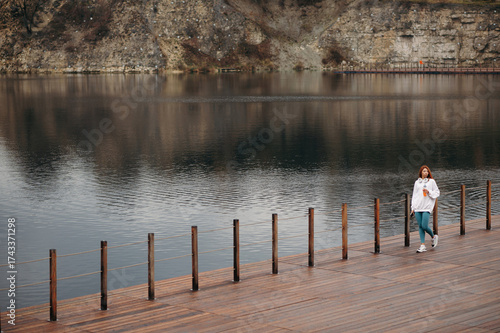 Woman walking wooden pier near big lake after sport looking distance